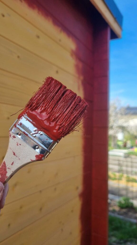 Ein Pinsel und unser Gartenhaus, dass wir schwedenrot gestrichen haben.