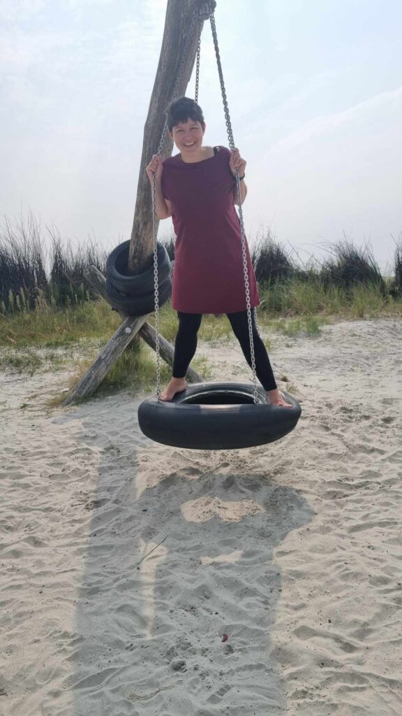 Ich stehe auf einer Reifenschaukel am Strand.