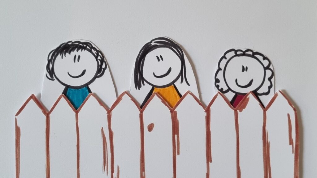 Drei gezeichnete Kinder schauen lächelnd über einen Zaun. Auf dem Bild sieht man nicht, dass sie auf 3 unterschiedlich großen Kisten stehen. Symbolbild für Gleichheit und Gerechtigkeit in der Pädagogik.