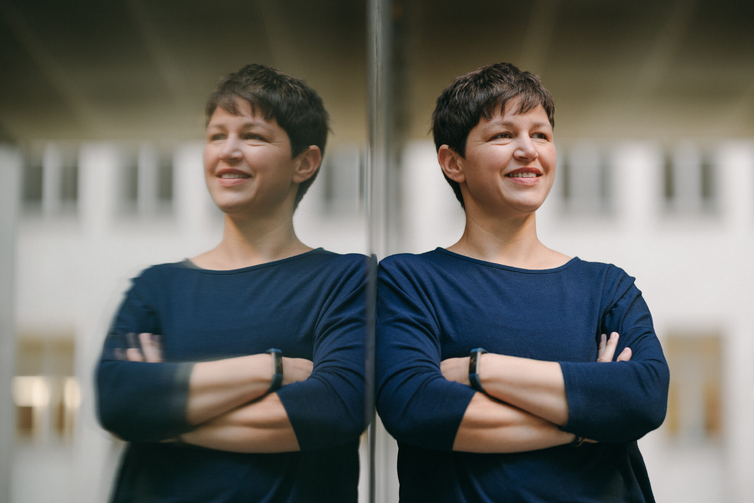 Professionelles Porträtfoto von Katja Andergassen, aufgenommen in Berlin. Sie trägt einen dunkelblauen Pullover. Es ist Katja Andergassen und ihr Spiegelbild zu sehen. Katja Andergassen bietet Weiterbildungen und Prozessbegleitungen für pädagogische Fachkräfte an. Fotografie von Markus Braumann