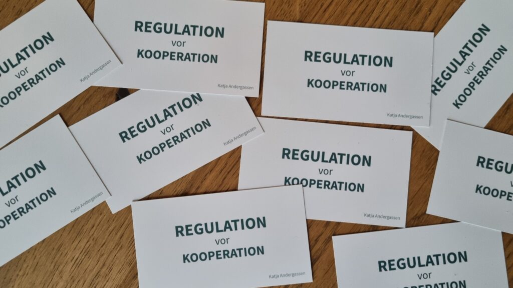 Visitenkarten von Katja Andergassen mit dem Text "Regulation vor Kooperation"
