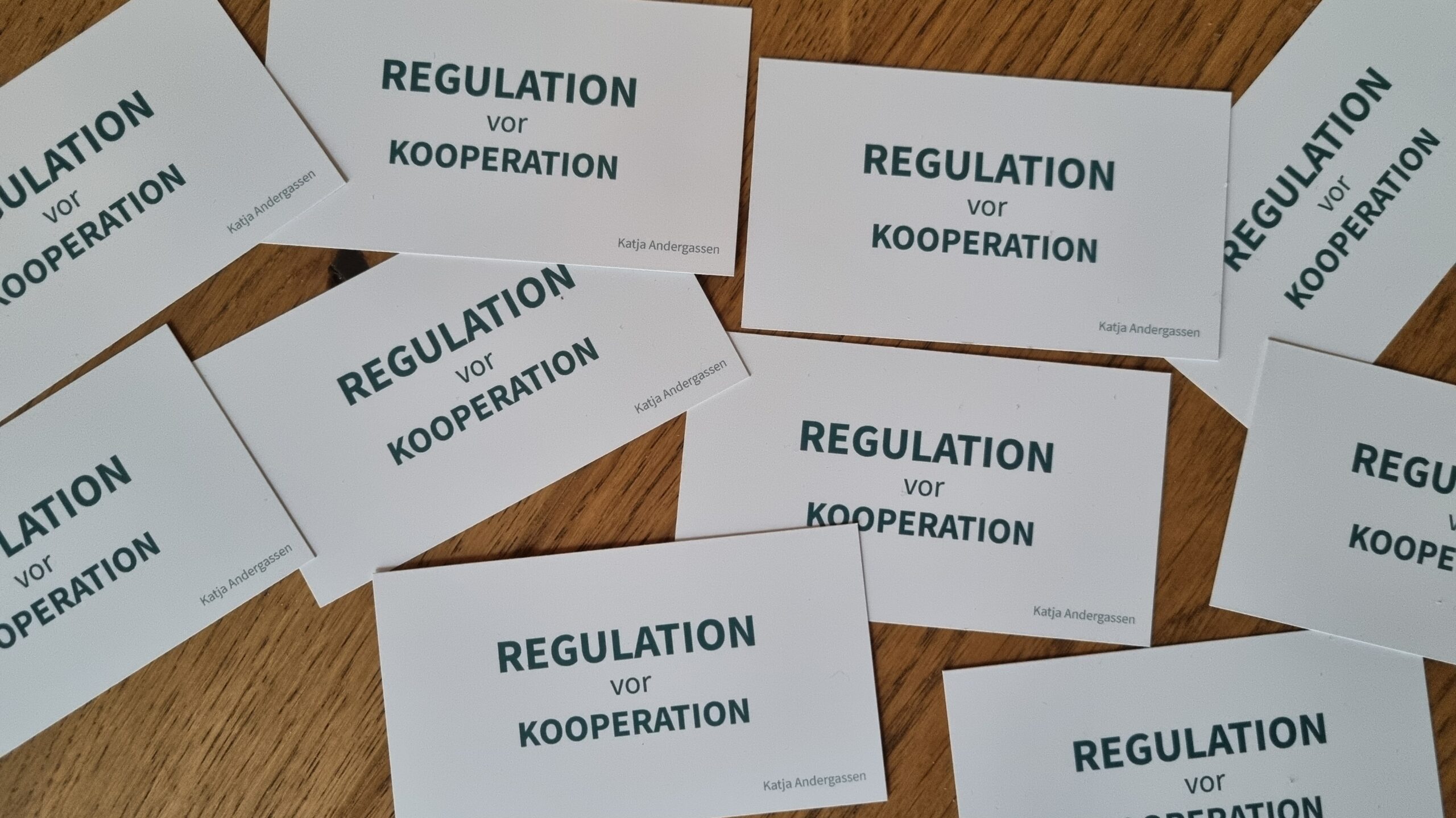 Visitenkarten von Katja Andergassen mit dem Text "Regulation vor Kooperation"